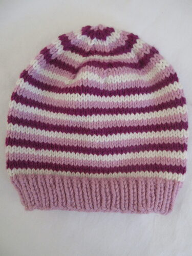 %%Handknit Adult Hat%%, Made and donated by Anne Morris, Peterborough, NH; Size small; Chunky washable wool blend; Pink, magenta and cream stripes.