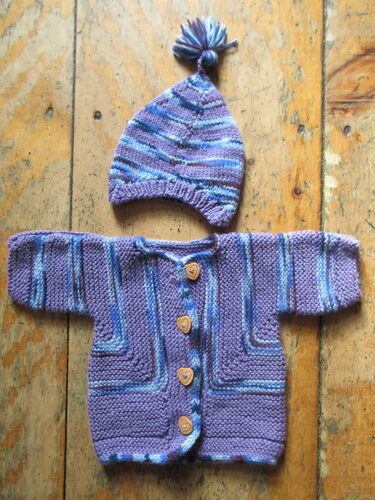 %%Handknit Sweater and Matching Hat%%, Donated by the Lord family; Size: Infant/Toddler; Acrylic yarn; Purples and blues; Wooden heart buttons.