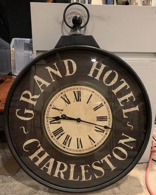 %%Huge Grand Hotel Charleston Wall Clock%%, Donated by the Irwin family; Previously owned in very good condition; Inspired by Charleston's historic district of hotels, this battery-operated wall clock is a nostalgic statement piece; Color & Finish: Aged black metal finish; Materials: Metal, pressed wood, and glass; Dimensions: 40.25h x 31w x 3.5d; AA battery required; Keyhole hanger; Value based on product when brand new.
